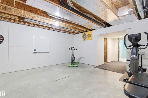 The property includes an unfinished basement with exposed ceiling joists and concrete flooring - 678 Secord Boulevard, Edmonton, AB - Indoor Photo Showing Gym Room