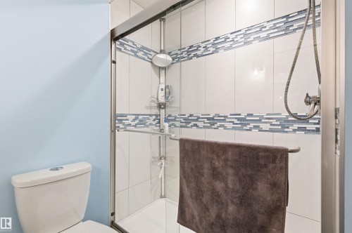 The bathroom features a toilet and a shower with a sliding glass door - 678 Secord Boulevard, Edmonton, AB - Indoor Photo Showing Bathroom