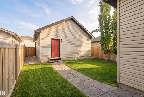 Detached garage with a vibrant red door, a paved pathway, and a well-maintained lawn area - 678 Secord Boulevard, Edmonton, AB - Outdoor With Exterior
