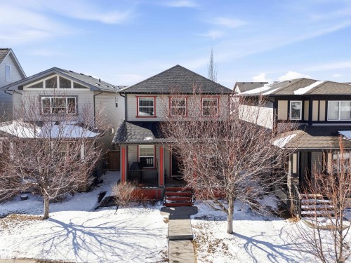 The property features a charming exterior with red trim detailing, a covered front porch, and a paved walkway leading to the entrance - 678 Secord Boulevard, Edmonton, AB - Outdoor