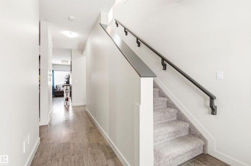 Entryway featuring hard surface flooring, a carpeted staircase with a dark handrail, and white walls - 678 Secord Boulevard, Edmonton, AB - Indoor Photo Showing Other Room
