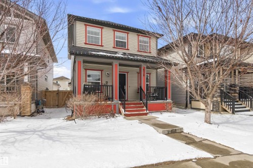 The property features a two-story exterior with light-colored siding and contrasting red trim around the windows and porch columns - 678 Secord Boulevard, Edmonton, AB - Outdoor