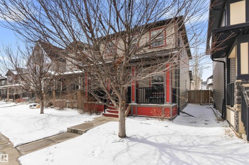 The property features a front porch with red accents and black railings, complementing the light-colored siding - 678 Secord Boulevard, Edmonton, AB - Outdoor