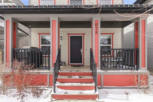 Inviting front porch with red and grey pillars, a dark paneled front door, and a black railing - 678 Secord Boulevard, Edmonton, AB - Outdoor