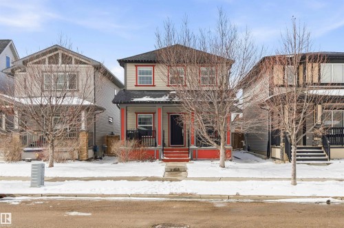 This property features a welcoming front porch with red accents, a dark front door, and a traditional facade with red trim around the windows - 678 Secord Boulevard, Edmonton, AB - Outdoor