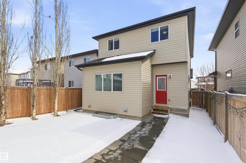 The property features a fenced yard, a red rear door, and a paved walkway - 678 Secord Boulevard, Edmonton, AB - Outdoor With Exterior