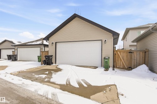 The property features a garage with a white overhead door and two exterior light fixtures - 678 Secord Boulevard, Edmonton, AB - Outdoor