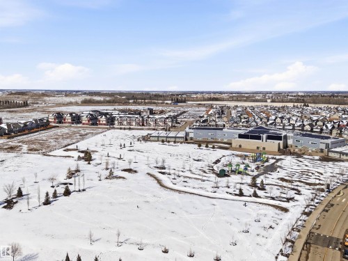 Aerial view showcasing the expansive grounds, nearby residential developments, and a visible playground area - 678 Secord Boulevard, Edmonton, AB - Outdoor With View
