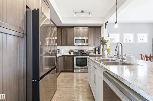 The kitchen features wood cabinetry, stainless steel appliances, and a double basin sink - 678 Secord Boulevard, Edmonton, AB - Indoor Photo Showing Kitchen With Double Sink With Upgraded Kitchen