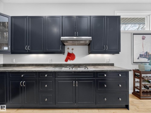 The kitchen features dark cabinetry, light countertops, and a gas cooktop with a range hood - 569 Butterworth Way, Edmonton, AB - Indoor