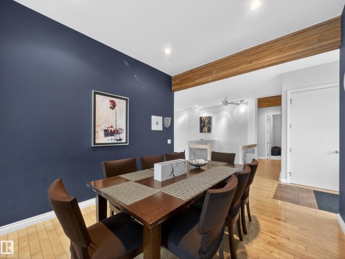 This dining area features hardwood flooring, a dark blue accent wall, and a wooden beam accent - 569 Butterworth Way, Edmonton, AB - Indoor Photo Showing Dining Room