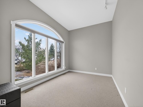 This room features a large arched window providing ample natural light and views of the surrounding trees - 569 Butterworth Way, Edmonton, AB - Indoor Photo Showing Other Room
