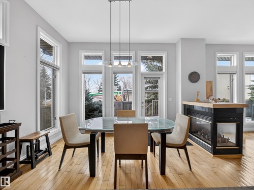 Dining area featuring hardwood floors, a glass-top dining table, and a linear pendant light fixture - 569 Butterworth Way, Edmonton, AB - Indoor Photo Showing Dining Room