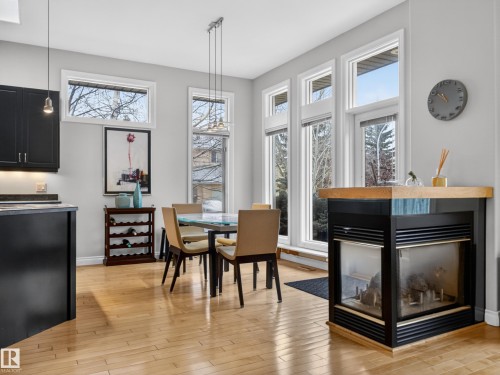 The property features hardwood floors, large windows providing natural light, and a fireplace with a wooden mantel - 569 Butterworth Way, Edmonton, AB - Indoor Photo Showing Dining Room With Fireplace