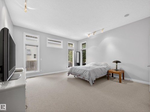 This inviting room features neutral-toned carpeting, ample natural light from several windows, and track lighting fixtures - 569 Butterworth Way, Edmonton, AB - Indoor Photo Showing Bedroom