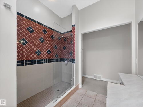 The bathroom features a walk-in shower with a glass enclosure, decorative tiled walls, and a tiled shower floor - 569 Butterworth Way, Edmonton, AB - Indoor