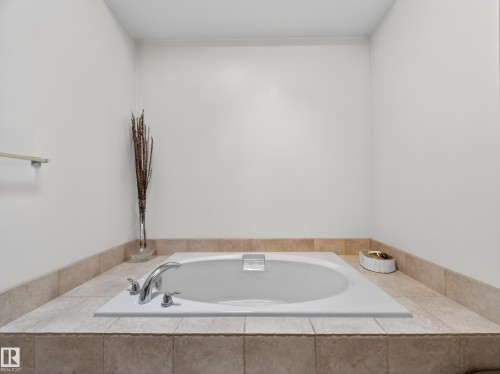 The bathroom features an integrated bathtub with chrome fixtures, set within a tiled surround - 569 Butterworth Way, Edmonton, AB - Indoor Photo Showing Bathroom