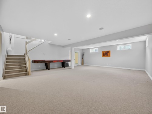 Expansive carpeted area with recessed lighting, a staircase with light wood railings, and windows providing natural light - 569 Butterworth Way, Edmonton, AB - Indoor Photo Showing Basement