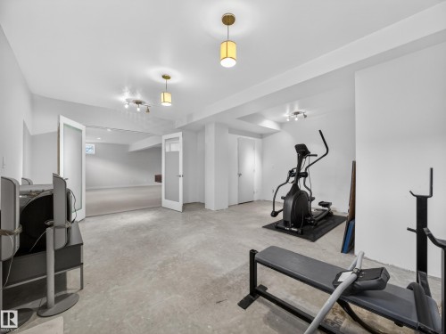 Spacious room featuring light gray walls, recessed lighting, and two sets of double doors with frosted glass panels - 569 Butterworth Way, Edmonton, AB - Indoor Photo Showing Gym Room