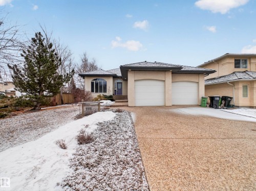 The property features a two-car garage, a concrete driveway, and a front yard with mature trees and shrubs - 569 Butterworth Way, Edmonton, AB - Outdoor