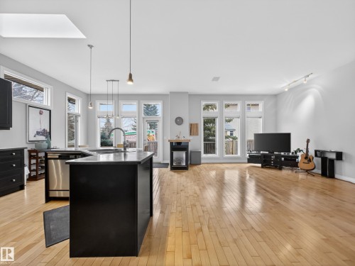 The open concept living area features light hardwood flooring and a skylight, enhancing the natural light from the numerous windows - 569 Butterworth Way, Edmonton, AB - Indoor