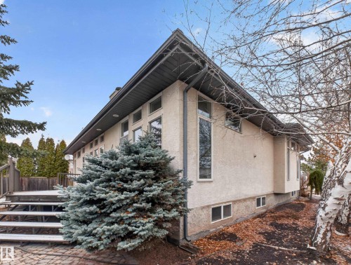 The property features a stucco exterior, a dark-colored roof, and a deck with wooden stairs - 569 Butterworth Way, Edmonton, AB - Outdoor