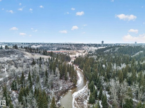 The property is situated within a scenic natural landscape, featuring a winding river, dense evergreen trees, and snow-dusted deciduous trees - 569 Butterworth Way, Edmonton, AB - Outdoor With View