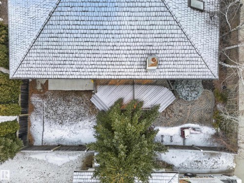 The property features a shingle roof, a spacious deck, and a circular paver patio with a decorative pattern - 569 Butterworth Way, Edmonton, AB - Outdoor