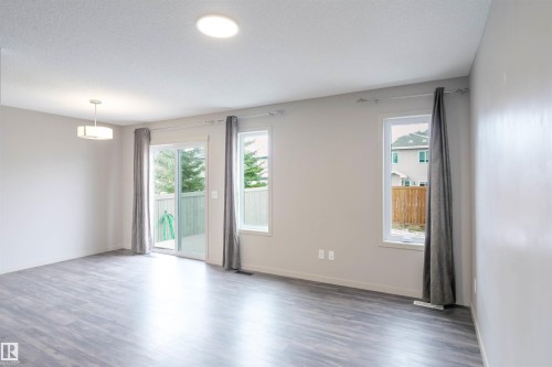 The property features modern wood-style flooring, a staircase with white risers and handrails, and a stainless steel side-by-side refrigerator - 1426 25 Avenue, Edmonton, AB - Indoor Photo Showing Other Room