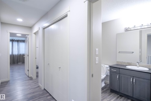 The property features modern wood-style flooring, a staircase with white risers and handrails, and a stainless steel side-by-side refrigerator - 1426 25 Avenue, Edmonton, AB - Indoor Photo Showing Other Room