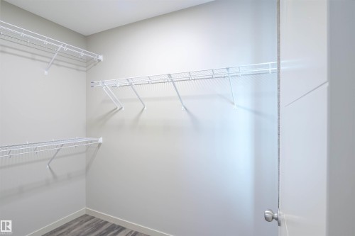 Powder room featuring a white toilet with a bidet sprayer, a stainless steel toilet paper holder, and wood-look flooring - 1426 25 Avenue, Edmonton, AB - Indoor Photo Showing Bathroom