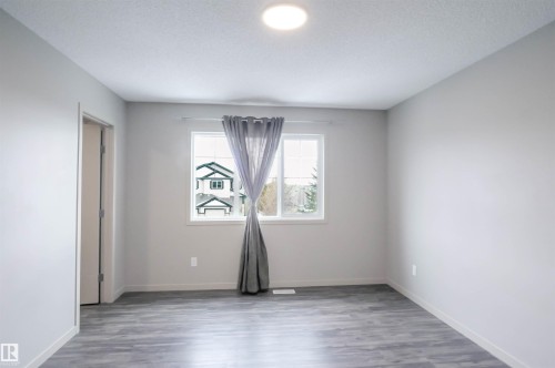 The room features light gray walls, wood-style flooring, and a window with gray curtains - 1426 25 Avenue, Edmonton, AB - Indoor Photo Showing Other Room
