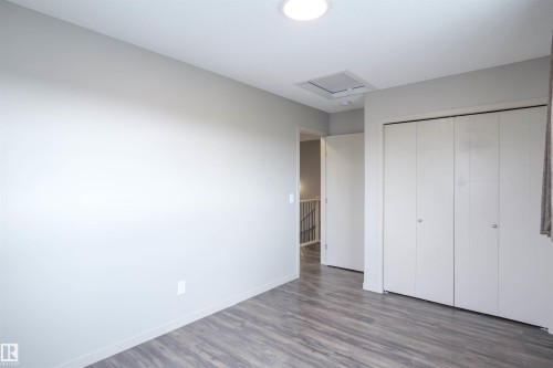 This inviting room features wood-look flooring and a light-colored accent wall - 1426 25 Avenue, Edmonton, AB - Indoor Photo Showing Other Room
