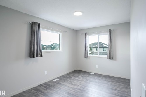 Bright room featuring two windows, light gray walls, and wood-style flooring - 1426 25 Avenue, Edmonton, AB - Indoor Photo Showing Other Room