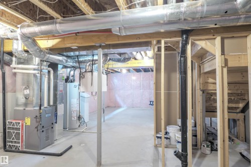 The unfinished basement features exposed wooden joists and ductwork, a furnace, and a water heater - 1426 25 Avenue, Edmonton, AB - Indoor Photo Showing Basement