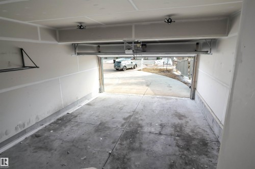 The garage features a concrete floor, white walls, and an overhead door mechanism - 1426 25 Avenue, Edmonton, AB - Indoor Photo Showing Garage