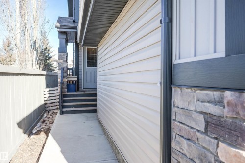 Exterior view showcasing the property's siding, stone facade, and a side entrance with a gray door - 1426 25 Avenue, Edmonton, AB - Outdoor With Exterior