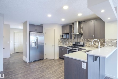 The property features a kitchen with grey cabinetry, stainless steel appliances, a mosaic tile backsplash, and light-colored countertops - 1426 25 Avenue, Edmonton, AB - Indoor Photo Showing Kitchen With Stainless Steel Kitchen With Upgraded Kitchen