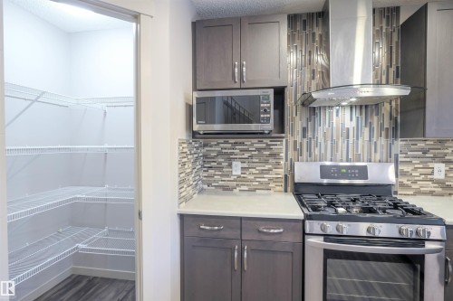 Kitchen featuring stainless steel appliances, including a gas range with an overhead range hood, and a microwave - 1426 25 Avenue, Edmonton, AB - Indoor Photo Showing Kitchen With Upgraded Kitchen