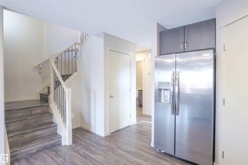 The kitchen features dark wood cabinetry, stainless steel appliances including a microwave, oven, and range hood, and a decorative tile backsplash - 1426 25 Avenue, Edmonton, AB - Indoor Photo Showing Other Room