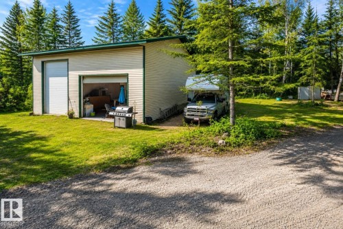 Detached garage building featuring light-colored siding, a green trim roofline, and two overhead doors - 635-59201 Range Rd 95, Rural St. Paul County, AB - Outdoor