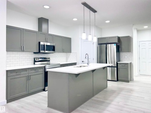 Kitchen featuring gray cabinets, stainless steel appliances, a center island with sink, and light wood-style flooring - 19634 29 Avenue, Edmonton, AB - Indoor Photo Showing Kitchen With Upgraded Kitchen