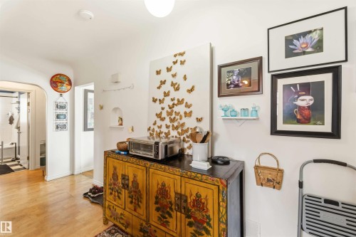 Light-toned wood-finish flooring extends through the hallway, complemented by white walls - 6036 106 Street, Edmonton, AB - Indoor Photo Showing Other Room
