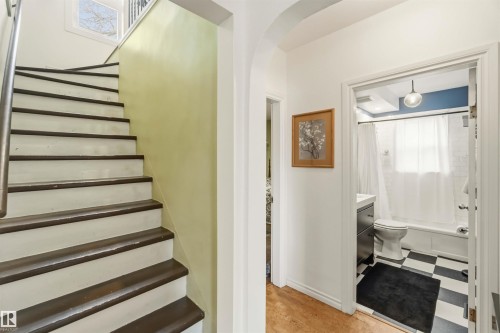 Wood-finish flooring extends into a hallway with an arched doorway - 6036 106 Street, Edmonton, AB - Indoor Photo Showing Other Room