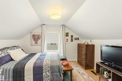Attic space featuring sloped ceilings, a flush mount ceiling light fixture, hardwood flooring, and a window with a roller blind - 6036 106 Street, Edmonton, AB - Indoor Photo Showing Bedroom