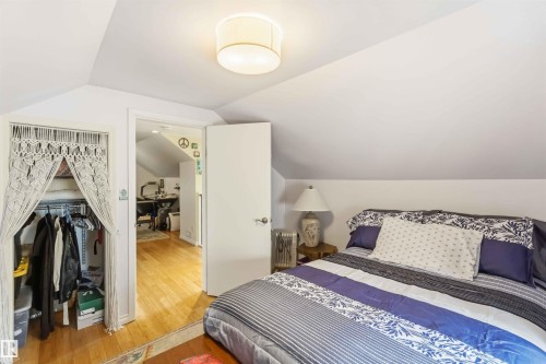 Sloped ceiling room featuring light wood-finish flooring, a flush-mount ceiling light, a built-in closet, and a white interior door - 6036 106 Street, Edmonton, AB - Indoor Photo Showing Bedroom