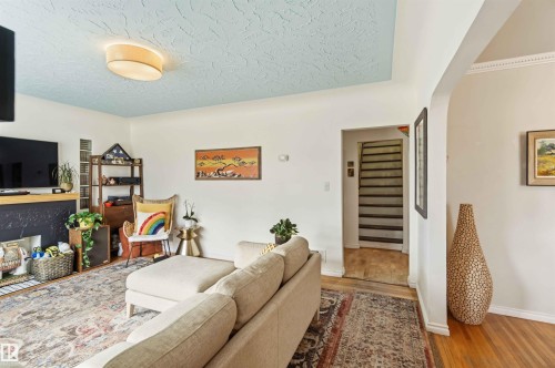 Living area featuring a fireplace with a black surround, a textured blue ceiling, and hardwood flooring - 6036 106 Street, Edmonton, AB - Indoor With Fireplace