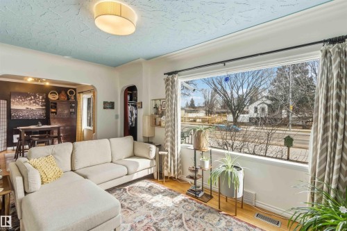 Expansive picture window illuminating the living area, featuring wood-finish flooring and a textured ceiling - 6036 106 Street, Edmonton, AB - Indoor Photo Showing Living Room