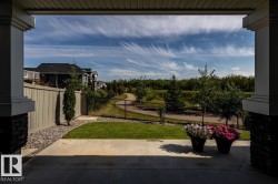 Concrete patio area with stone pillar accents, manicured lawn, and a light-colored privacy fence - 