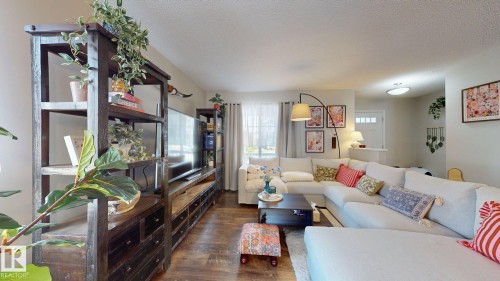 The living room features hardwood flooring and an entertainment center with shelving and storage - 1275 Chappelle Boulevard, Edmonton, AB 